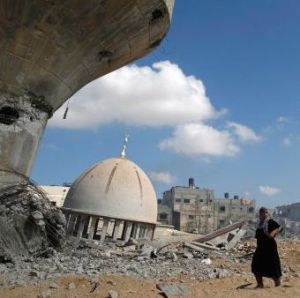 Palestinian women walk by mosque and water tower Israeli air strikes and shelling Khuzaa, east of Khan Younis, in southern Gaza Strip. August 3, 2014.  AFP
